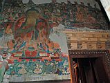 Lo Manthang Thubchen 04-1 Entrance Left Of Door Painting Of Buddha A large painting of golden Buddha in the teaching mudra is to the left of the assembly hall entrance door at Thubchen Gompa in Lo Manthang (658), with another smaller painting of Buddha above the door.